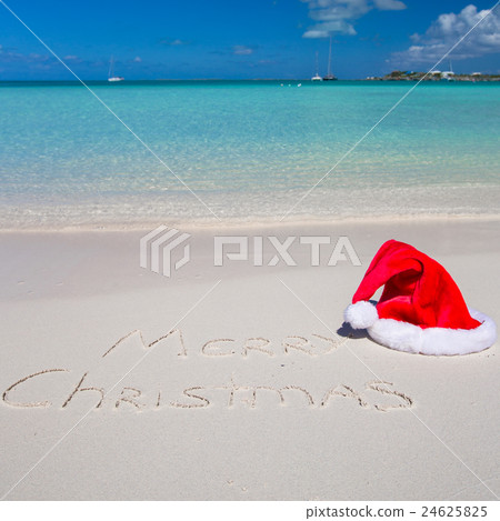 Santa Hat on white sandy beach and Merry Christmas 24625825