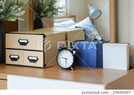 black alarm clock on wooden table in cozy bedroom 24640907