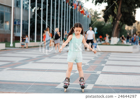 Little girl on roller skates in helmet at a park Little girl on roller skates in helmet at a park 24644297