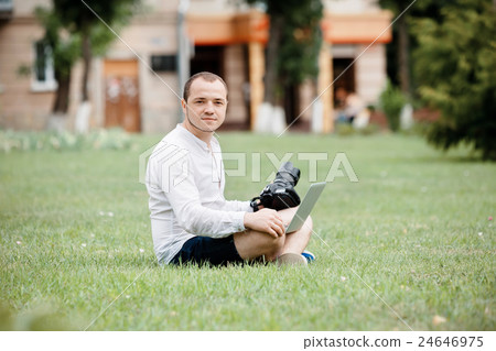 Young man photographer using laptop and camera in 24646975
