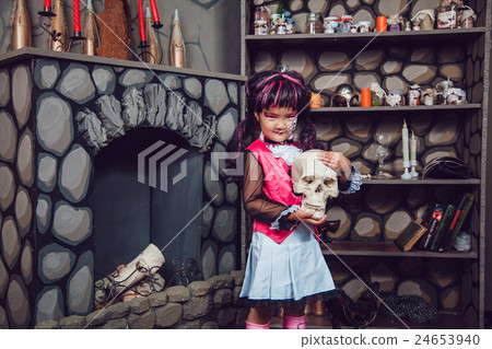 Girl in a witch costume is  skull in his hand in 24653940