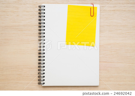 Yellow memo note clip on notebook on wooden table 24692042
