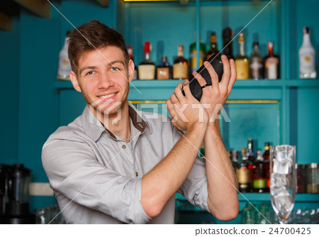 Young handsome barman in bar shaking and mixing Young handsome barman in bar shaking and mixing 24700425