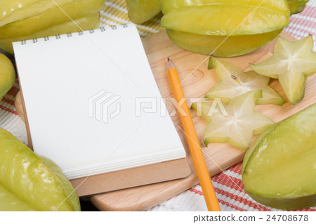 Star apple and notebook on wooden block. 24708678