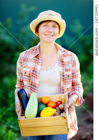 Female gardener holding wooden crate with fresh vegetables Female gardener holding wooden crate with fresh vegetables 24710941