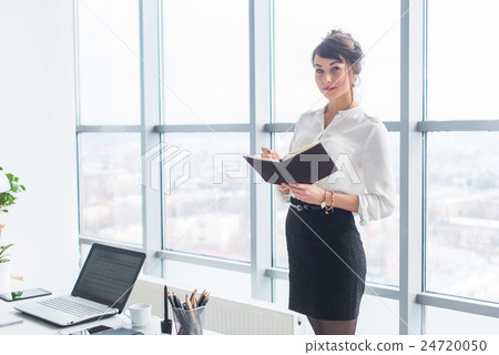 Beautiful female clerk standing in office at her Beautiful female clerk standing in office at her 24720050
