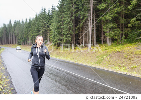 Young woman jogging on rainy road in mountains 24721092