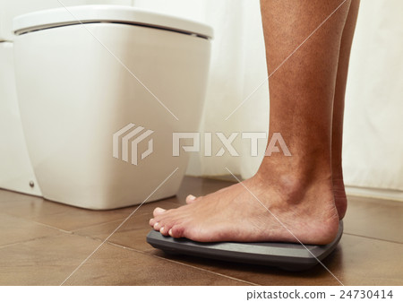 young man standing on a scale 24730414