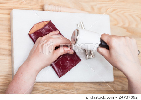 craftsman corrects embossing of leather pouch 24737062