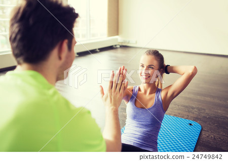 woman with personal trainer doing sit ups in gym 24749842