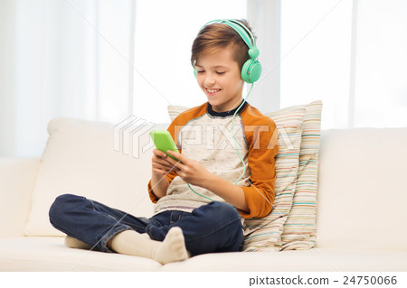 happy boy with smartphone and headphones at home happy boy with smartphone and headphones at home 24750066