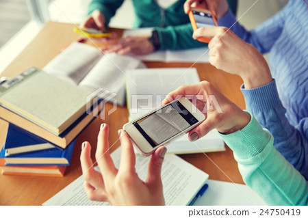 students with smartphones making cheat sheets 24750419