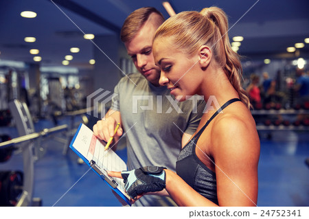 smiling woman with trainer and clipboard in gym 24752341
