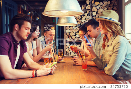 friends with smartphones and drinks at bar 24753750
