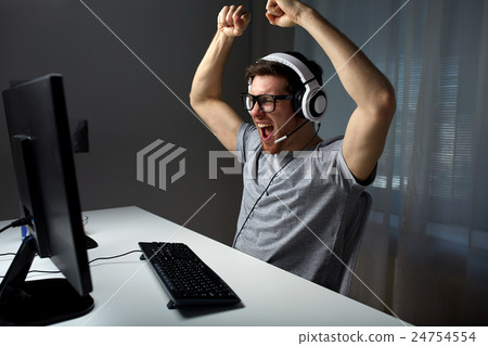 man in headset playing computer video game at home man in headset playing computer video game at home 24754554