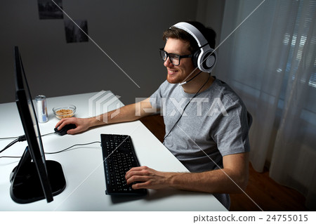 man in headset playing computer video game at home man in headset playing computer video game at home 24755015