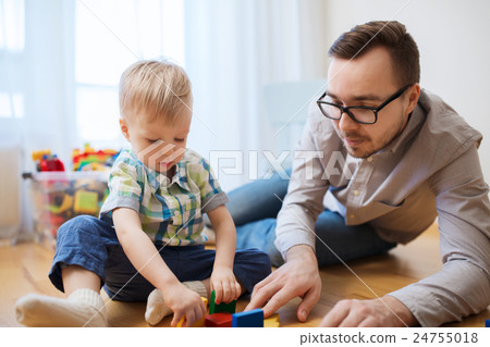 father and son playing with toy blocks at home 24755018