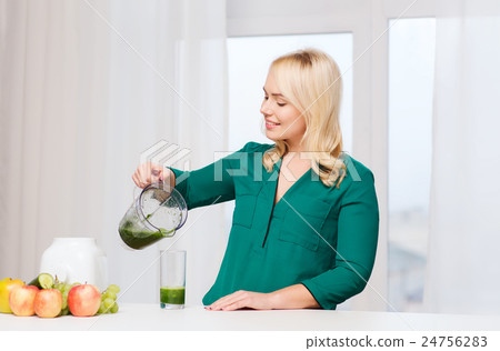 happy woman with blender jug pouring juice at home 24756283