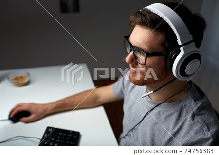 man in headset playing computer video game at home man in headset playing computer video game at home 24756383