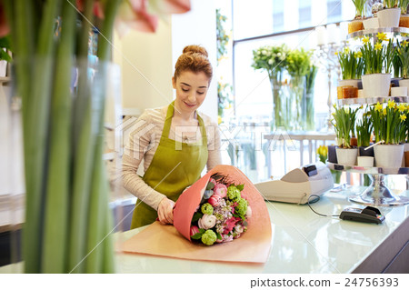 smiling florist woman packing bunch at flower shop 24756393