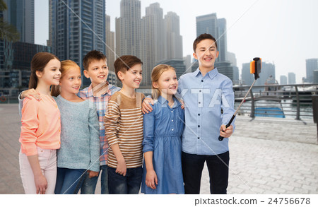 happy children with smartphone and selfie stick 24756678