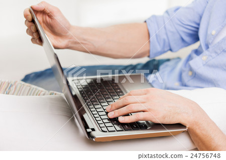close up of man typing on laptop computer at home 24756748