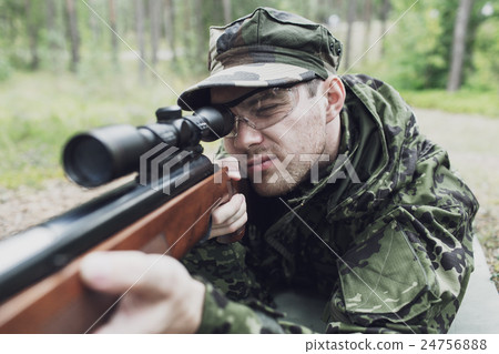 close up of soldier or hunter with gun in forest 24756888