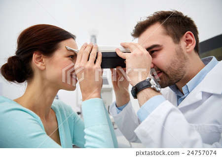 optician with pupilometer and patient at eye clinic optician with pupilometer and patient at eye clinic 24757074