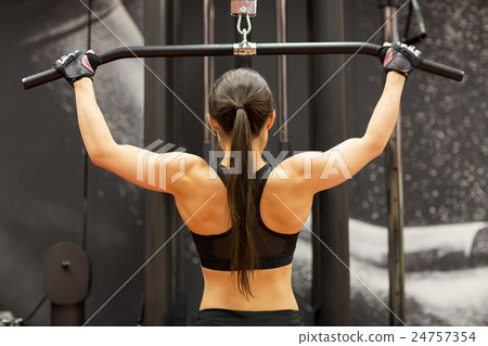 woman flexing muscles on cable machine in gym woman flexing muscles on cable machine in gym 24757354