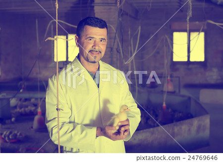 Glad man in white coat having duckling in hands 24769646