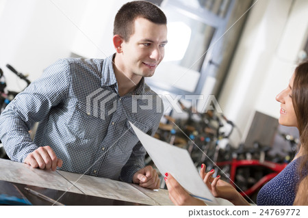 employee helping adult guy to select bike at rental agency employee helping adult guy to select bike at rental agency 24769772