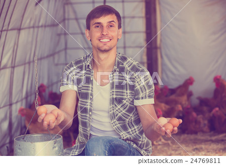 Male farmer picking fresh eggs in coop. Male farmer picking fresh eggs in coop. 24769811