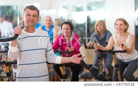 Elderly man on fitness cycle in fitness club. Elderly man on fitness cycle in fitness club. 24770536