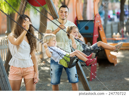 Daughters on swings with parents 24770722