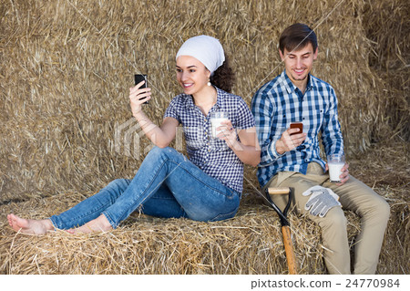 Young merry man and woman sitting together in the hay 24770984