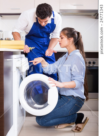 Repairman and woman near washing machine. 24771343