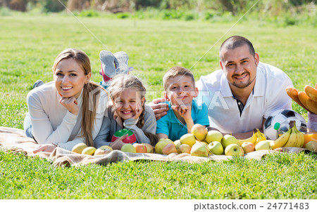 Happy mother and father with two teenagers lying in the garden 24771483