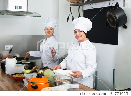 Two young women chefs cooking food at kitchen 24771605