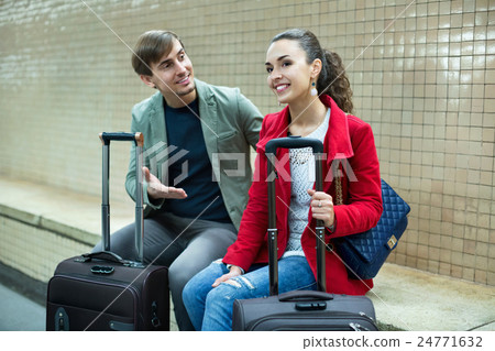 Smiling passengers with luggage waiting for train Smiling passengers with luggage waiting for train 24771632