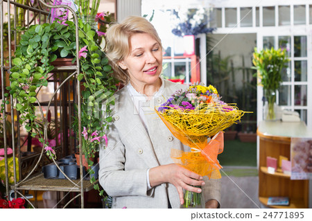 Cheerful mature blond woman selecting flowers 24771895