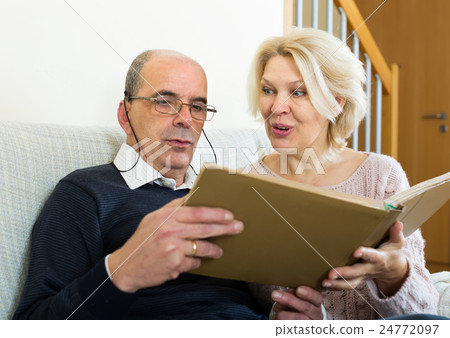 Senior spouses with picture album indoor Senior spouses with picture album indoor 24772097