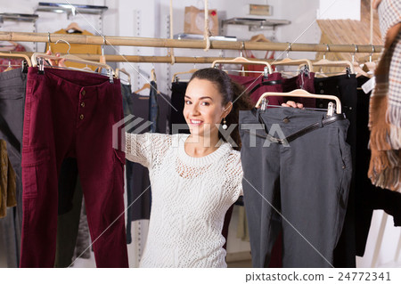 Young female brunette choosing trousers in shop Young female brunette choosing trousers in shop 24772341