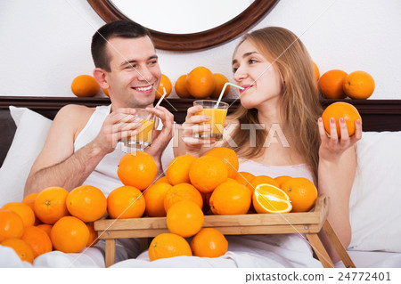 Young cheerful smiling couple with ripe oranges Young cheerful smiling couple with ripe oranges 24772401