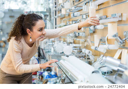 Girl selecting lighting units for interior Girl selecting lighting units for interior 24772404