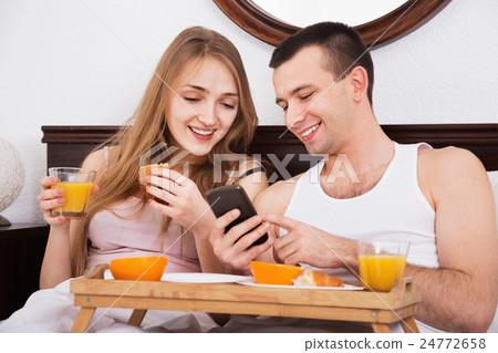 Young smiling couple reading news from smartphone 24772658
