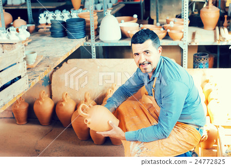 man potter holding ceramic vessels in atelier 24772825