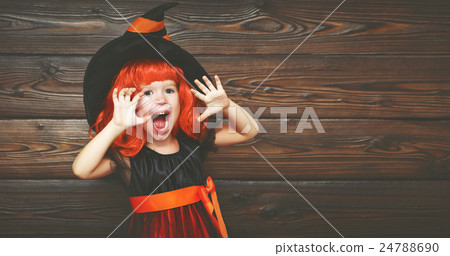 funny child girl in witch costume for Halloween scares 24788690