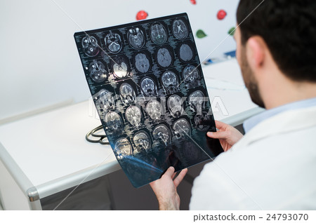 Young male physician reading and reviewing a MRI Young male physician reading and reviewing a MRI 24793070