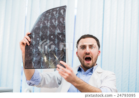 Scared worried doctor reviewing X-ray scan looking Scared worried doctor reviewing X-ray scan looking 24793095