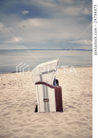 Retro toned hooded wicker chair on empty beach. 24794973